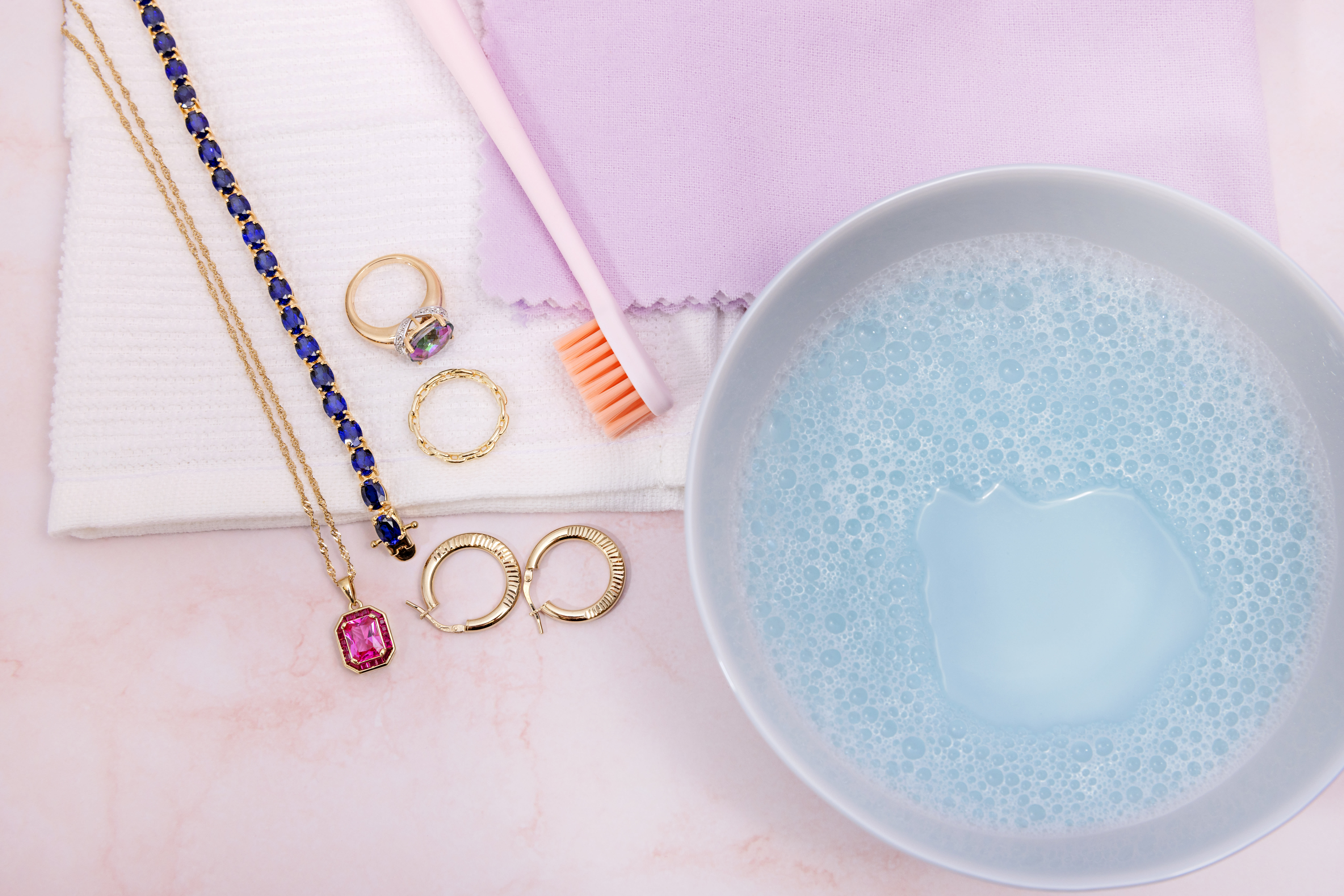 a collection of gold jewelry with cleaning supplies