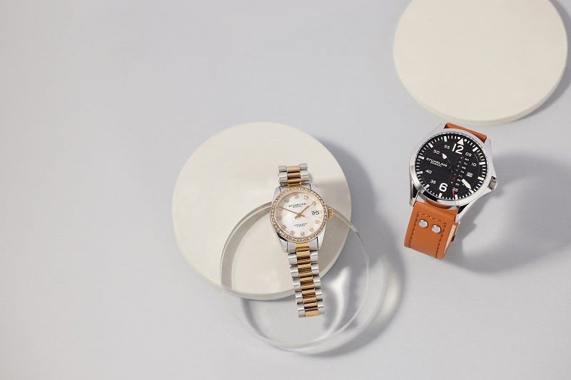 a stuhrling original watch with brown leather strap and a silver and gold watch