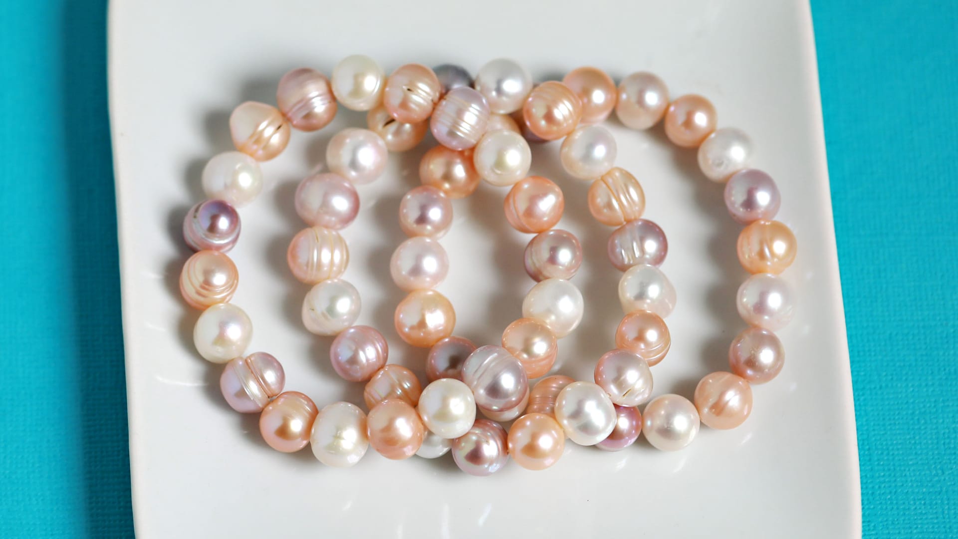 a group of peach and white pearl strand necklaces 