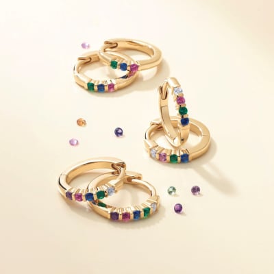 several huggie hoop earrings with different colors of gemstones 