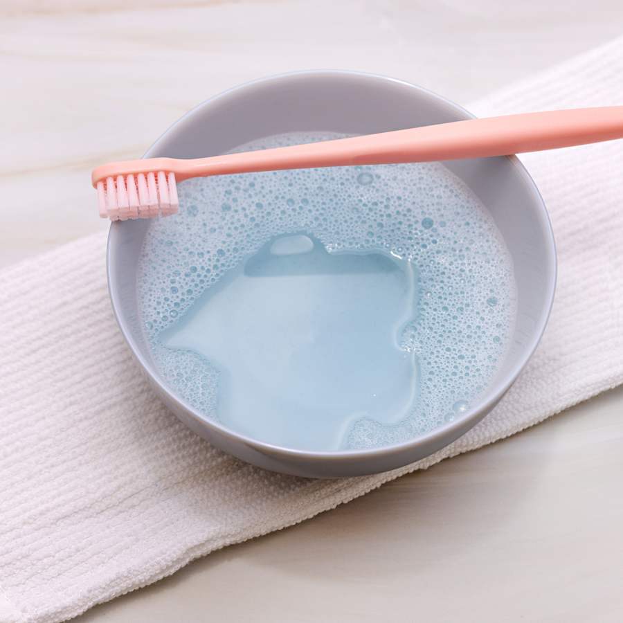 a toohbrush and bowl of soapy water 