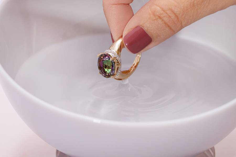 a multicolored gemstone ring is dipped in water 
