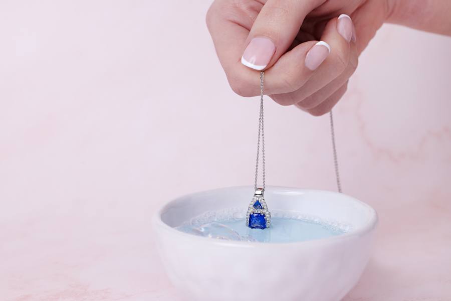 a blue gemstone, platinum pendant is dipped in water 