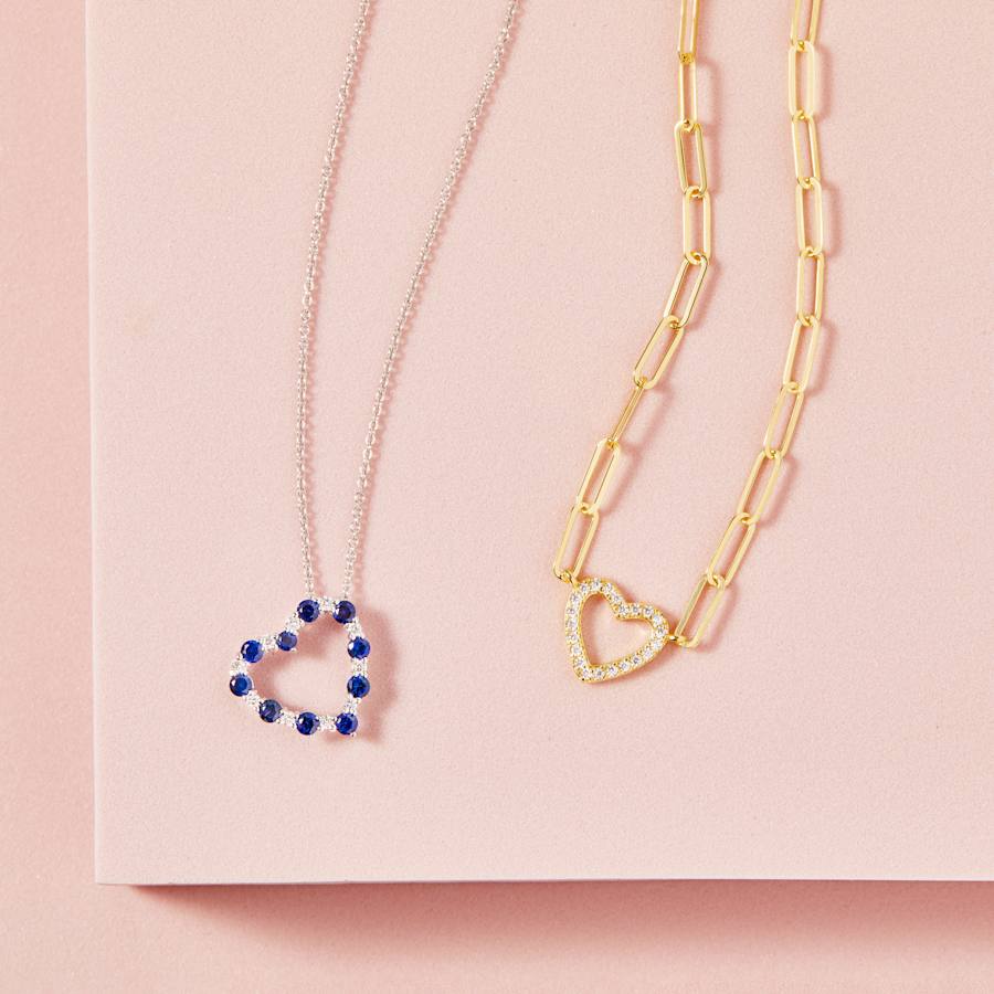 A heart-shaped silver blue sapphire necklace and a gold paperclip chain heart necklace 