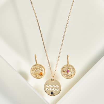 two gold symbolic dangle earrings and pendant