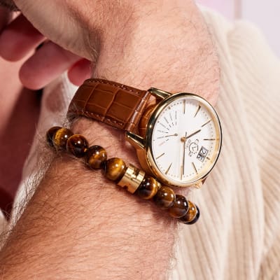 man's are wearing brown beaded bracelet and brown leather watch 