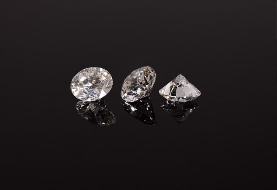 Three loose, faceted diamonds against a black background 