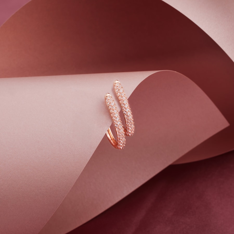 A pair of rose gold hoop earrings encrusted with white sapphire gemstones 