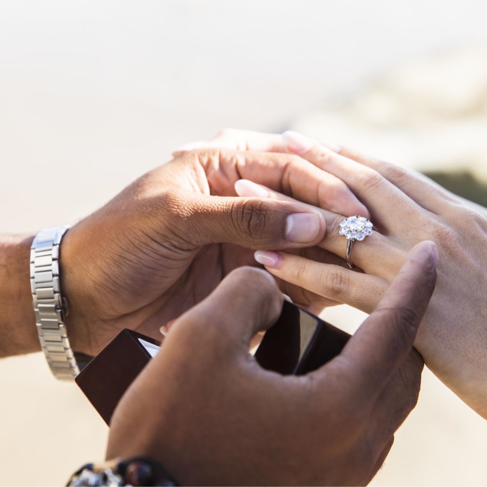 man placing an engagement ring on a woman's hand 