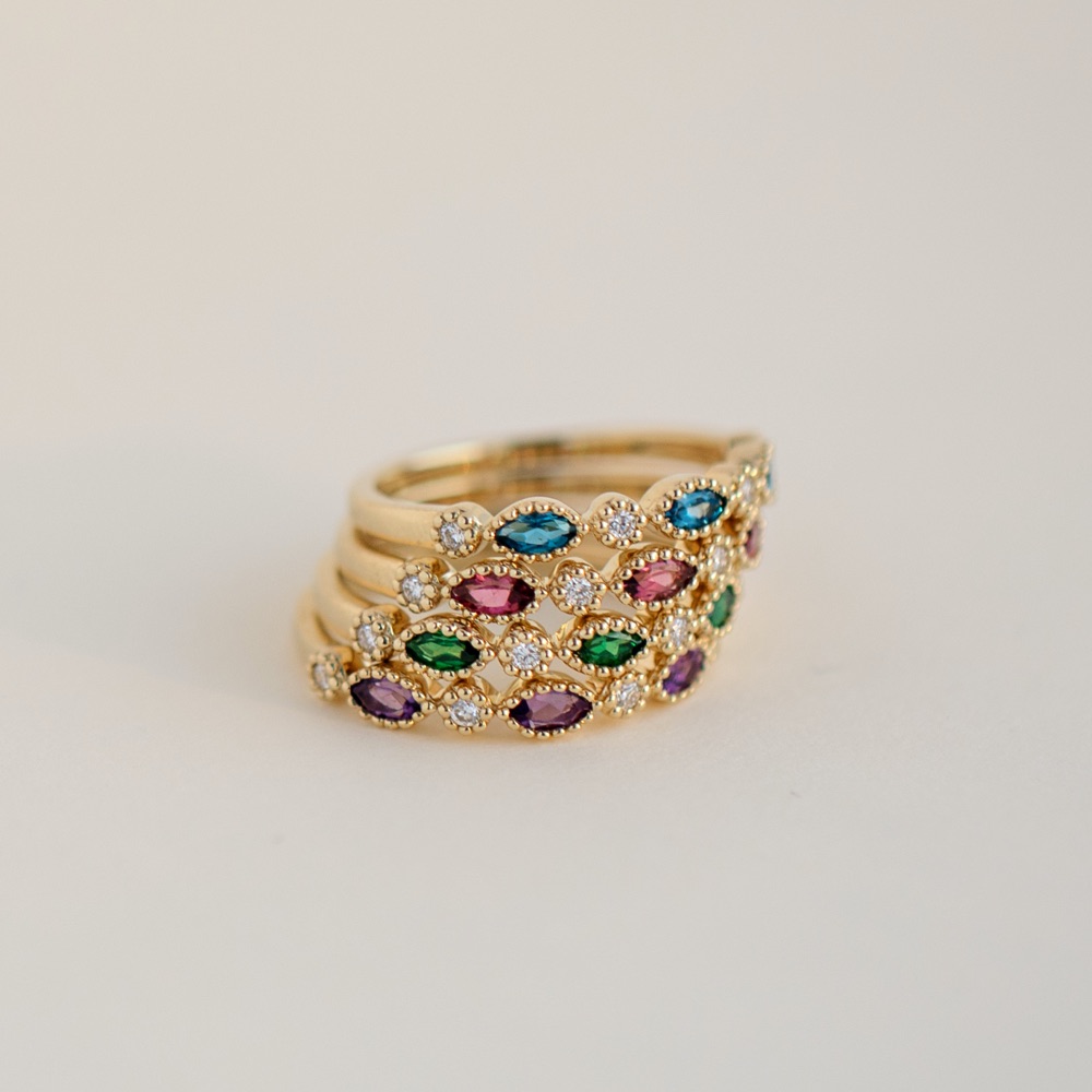 Stack of gold gemstone band rings in different colors 