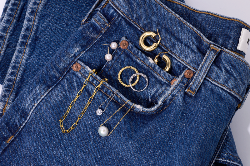 Dainty jewelry styles sitting on a pair of jeans